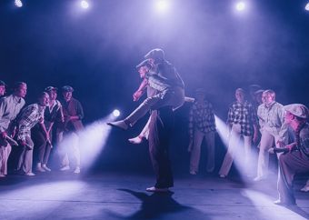 Ungdommer på en scene, der en gutt bærer en annen på ryggen mens flere står rundt dem.